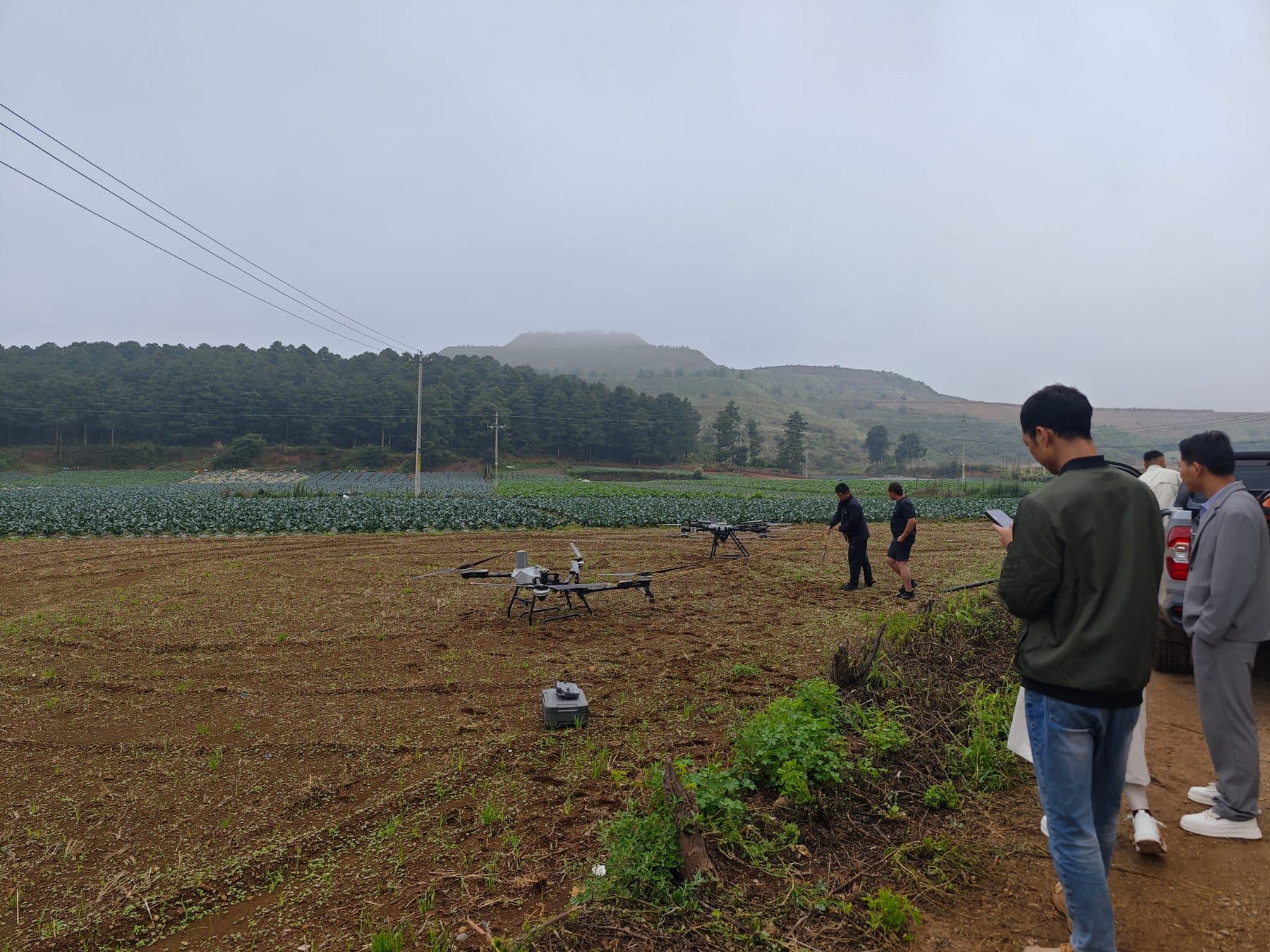 云南农业低空服务首飞现场，飞手与保障团队在田间进行无人机作业准备